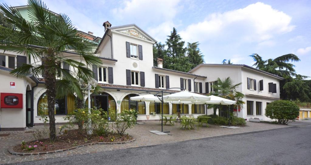 a large white building with umbrellas in front of it at Hotel Ristorante La Grotta in Castiglione delle Stiviere