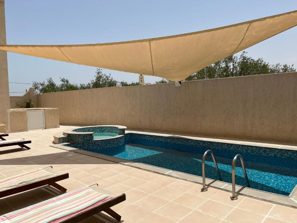 uma piscina com um guarda-sol num pátio em Residence Djerba em Midoun