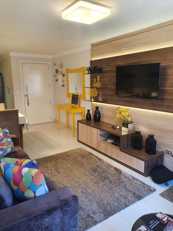 uma sala de estar com uma televisão de ecrã plano na parede em Temporada Gramado e Canela- Apartamento Centro Catedral em Canela