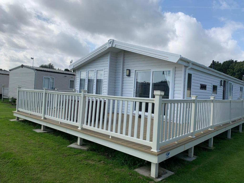8 BIRTH LODGE ON CAYTON BAY HOLIDAY PARK في سكرابورو: منزل متنقل مع شرفة وسطح