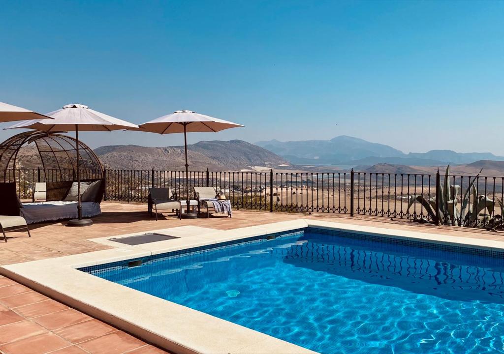 a swimming pool with chairs and umbrellas on a patio at Casa La Calera - Adults Only in Teba