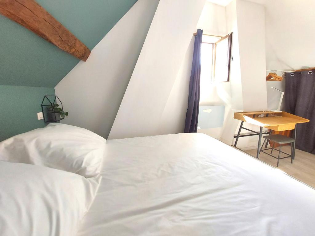 1 dormitorio con cama blanca y mesa en Le Capucin Serein, en Coulommiers