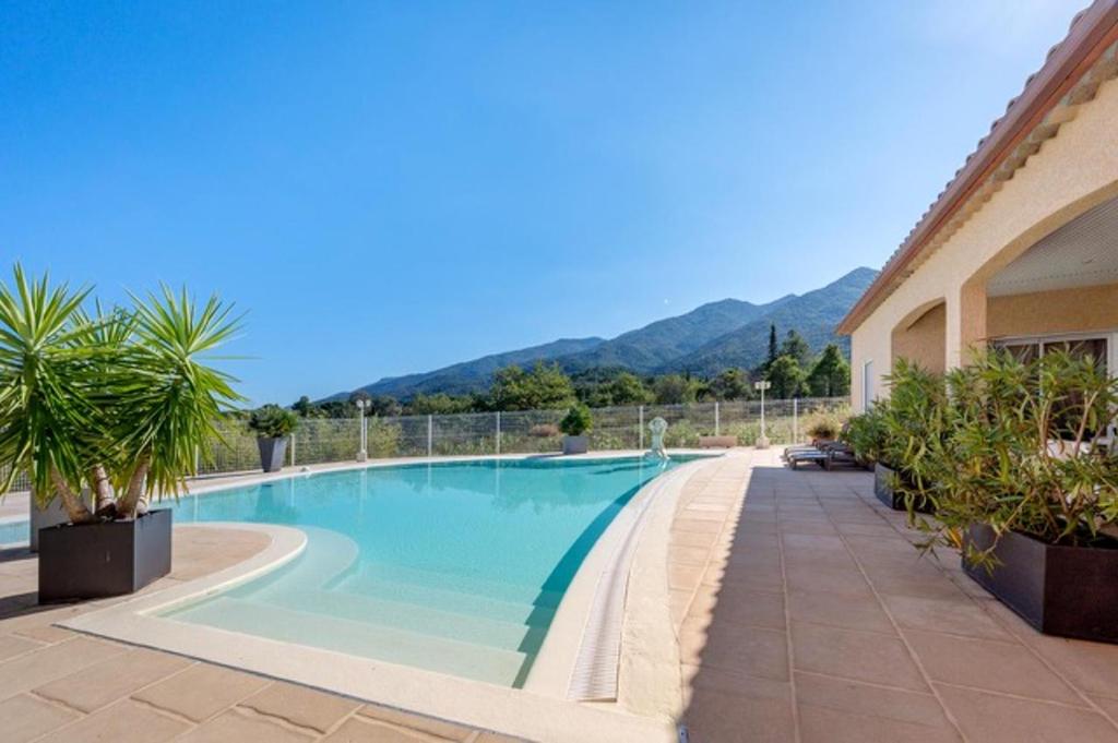een zwembad in een resort met bergen op de achtergrond bij Maison de 2 chambres avec piscine privee terrasse amenagee et wifi a Montesquieu des Alberes in Montesquieu