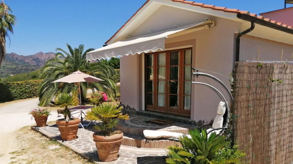 a small house with an umbrella and some plants at Villetta I Due Pini in Capoliveri