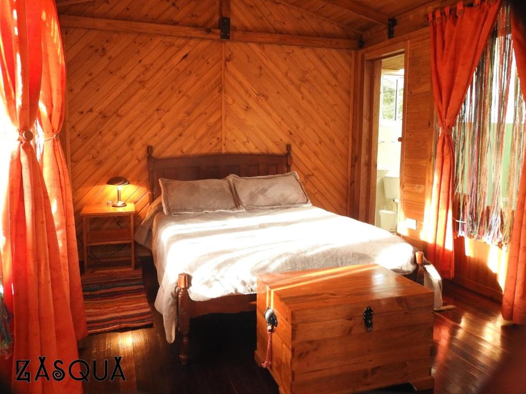 1 dormitorio con 1 cama en una cabaña de madera en Zasqua Glamping, en El Cape