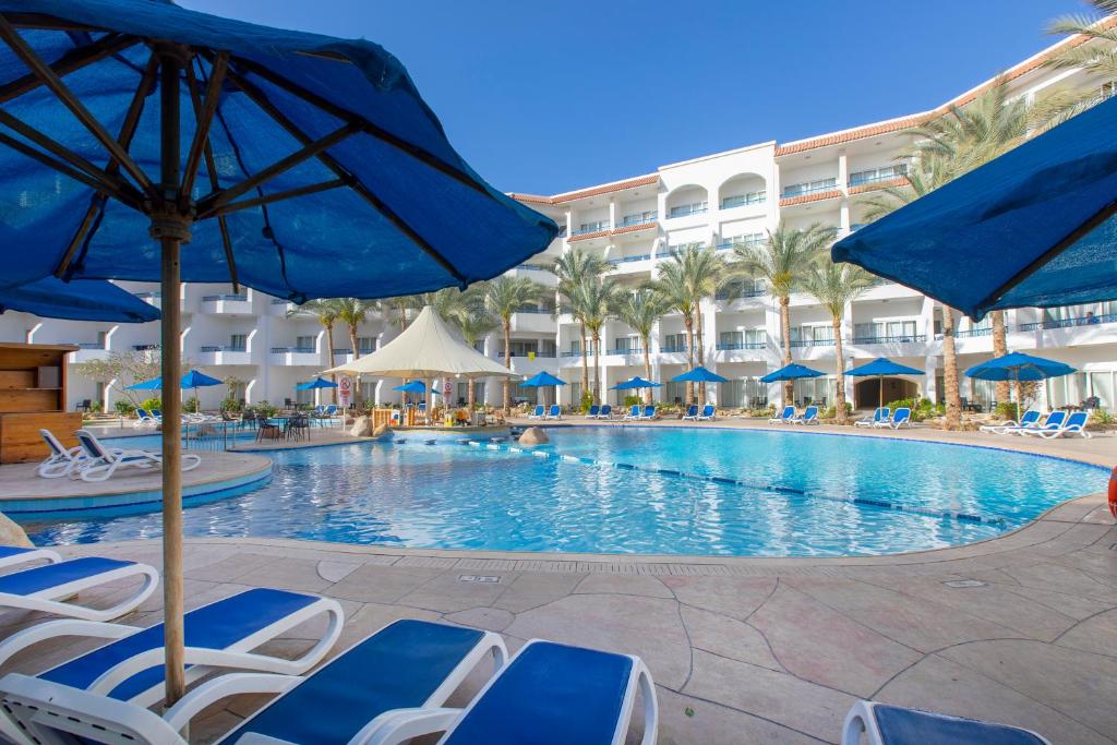 a pool at a resort with chairs and umbrellas at Naama Bay Hotel & Resort in Sharm El Sheikh