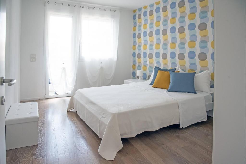 um quarto com uma cama branca com almofadas azuis e amarelas em Appartamenti Scrovegni em Pádua