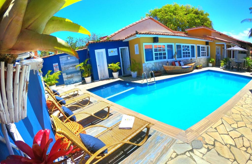 una piscina con sillas y una casa en Pousada Solar de Geribá en Búzios