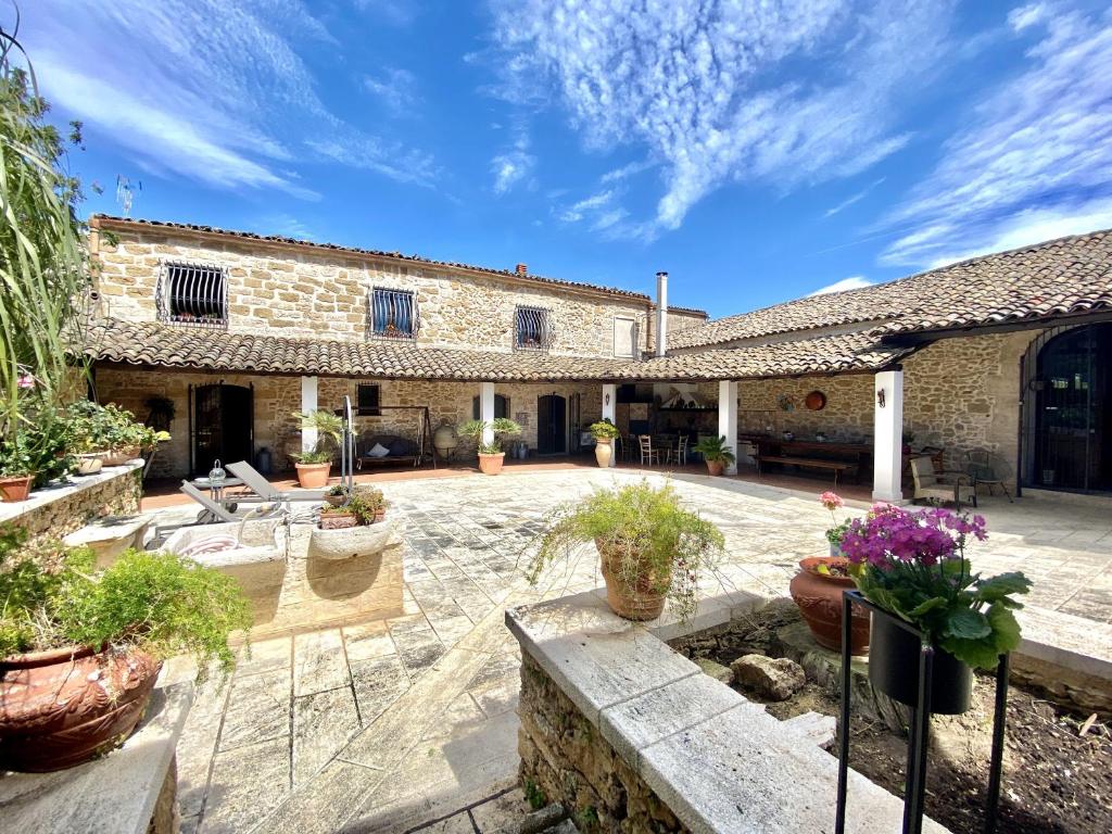 eine Außenterrasse mit Topfpflanzen und einem Gebäude in der Unterkunft Baglio Giganti in Alcamo