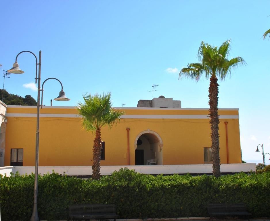 un edificio giallo con palme di fronte di Monolocali a Palazzo Rizzelli a Santa Cesarea Terme