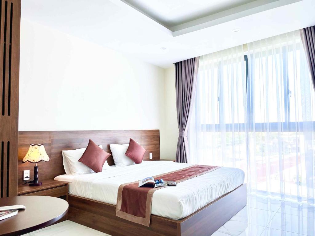 a bedroom with a bed and a large window at Marina Hotel Bình Dương in Thu Dau Mot