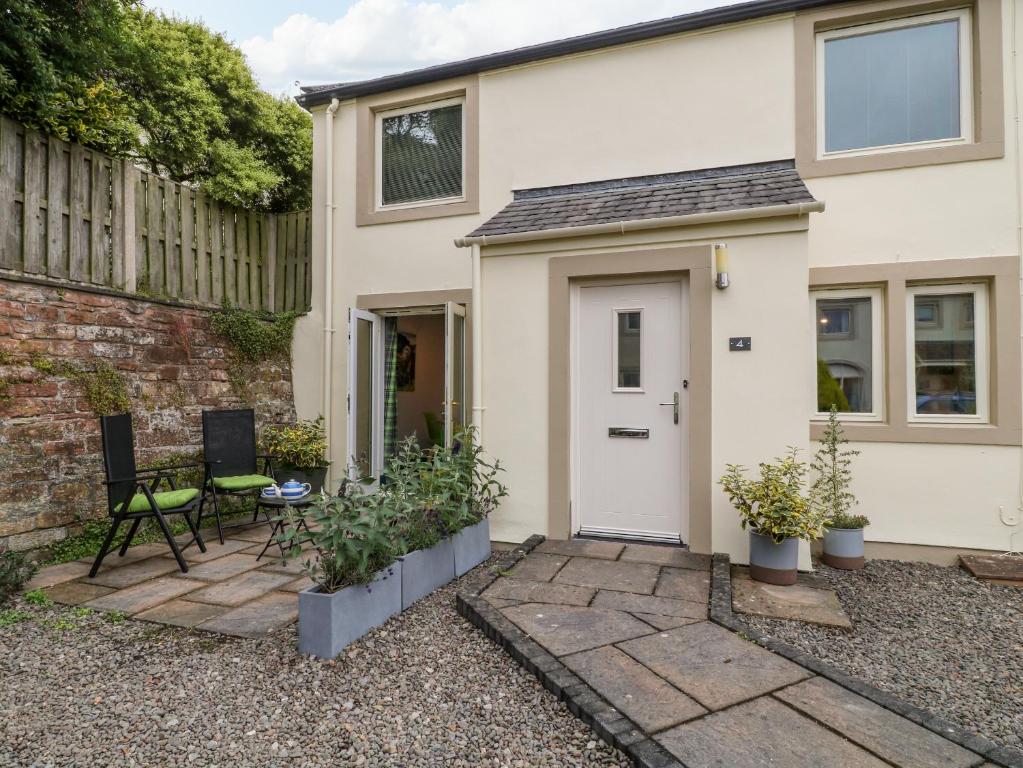 een huis met een witte deur en een patio bij Herdwick Cottage in Brampton