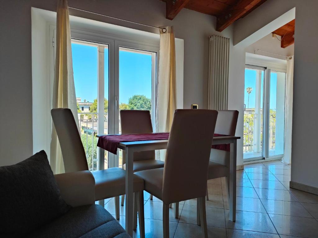 comedor con mesa, sillas y ventanas en Da Cate - Appartamento al mare, en Grottammare