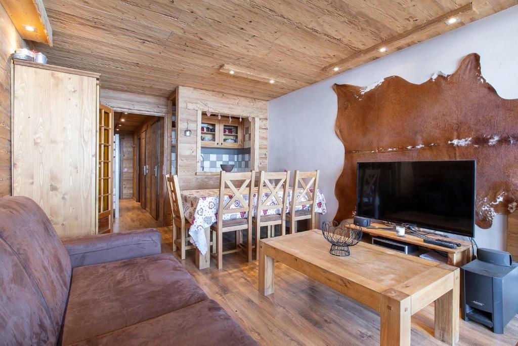 a living room with a couch and a tv and a table at Résidence Le Sérac - Val Thorens in Val Thorens