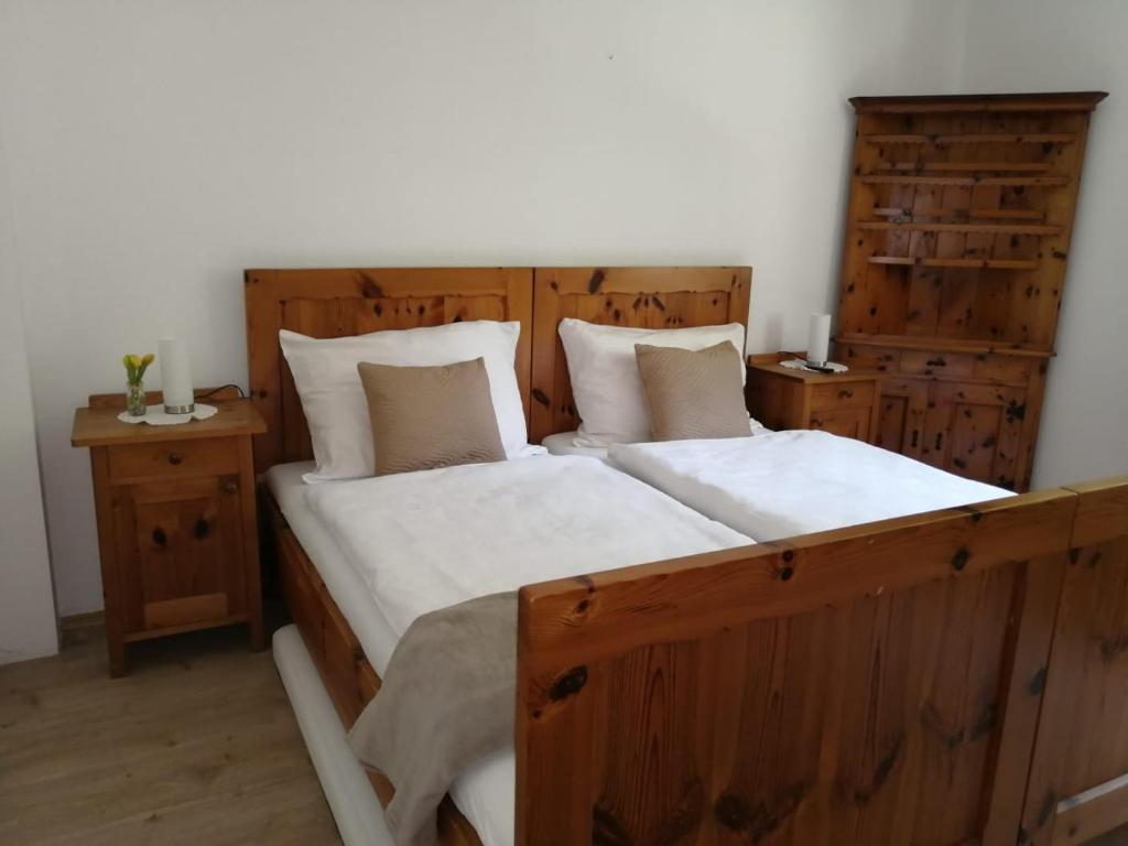 a bedroom with a wooden bed with white sheets and pillows at Apartment Hörmann in Ardning