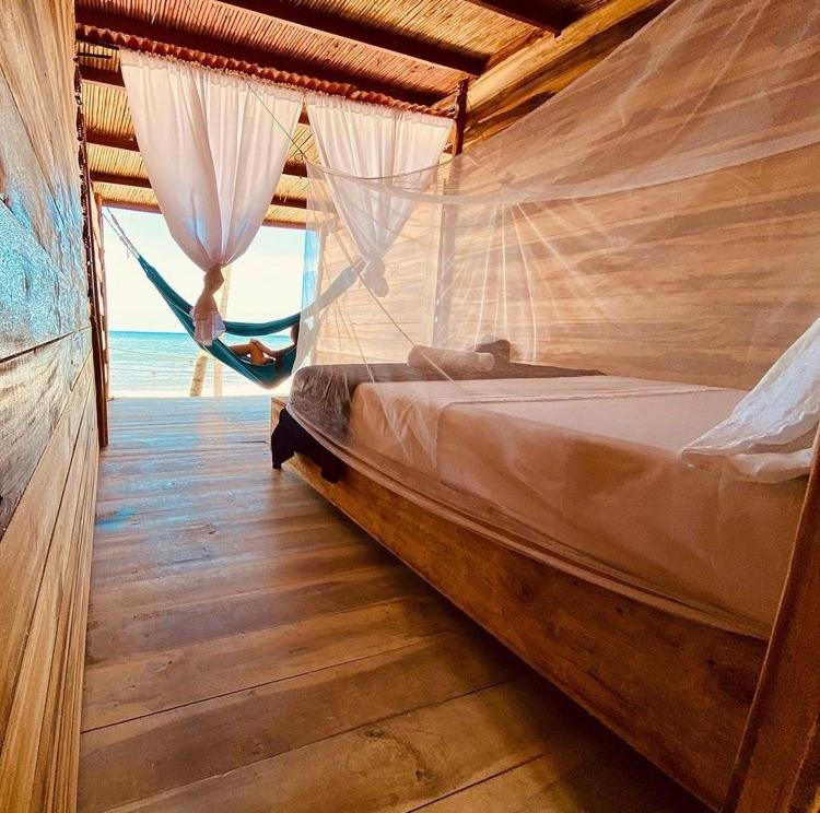 a bed with a hammock in a room with the ocean at Calma Chicha in Santa Marta