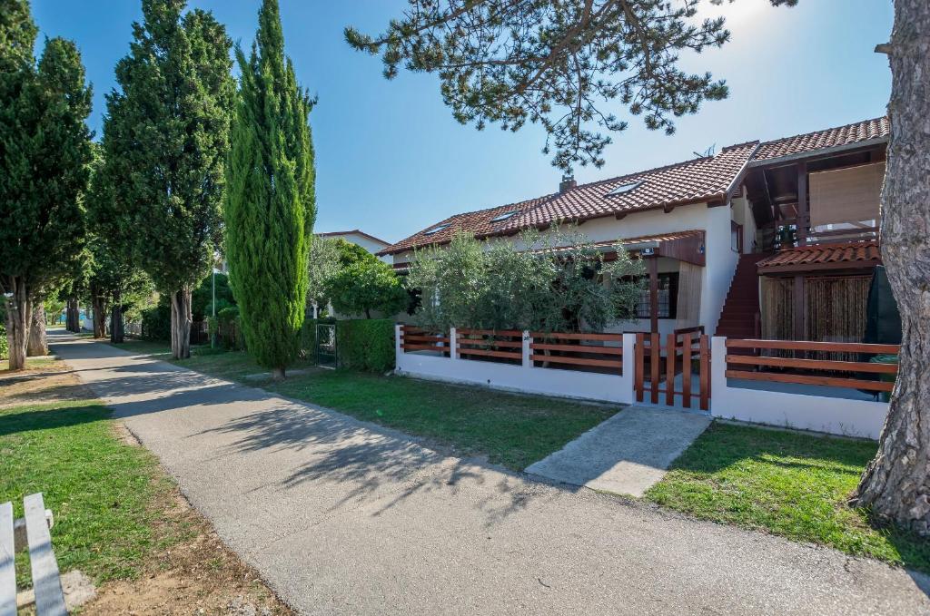 a house with a fence and trees on a street at Apartments Green Street in Batalaži