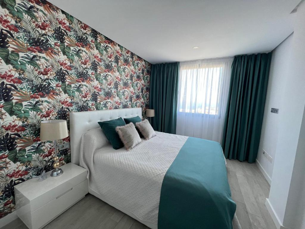 1 dormitorio con 1 cama y papel pintado con motivos florales en Luxury apartment in Ocean Garden Playa Paraiso, en Arona