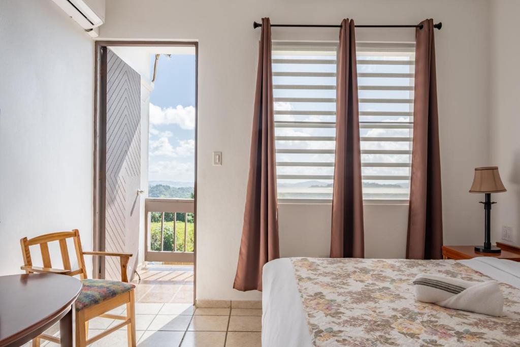 1 dormitorio con cama, mesa y ventana en Hacienda Margarita, en Barranquitas