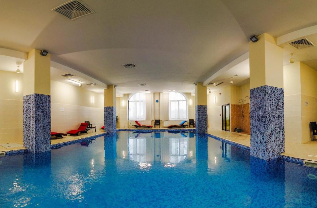 a swimming pool with blue water in a building at Hotel Carmen in Predeal