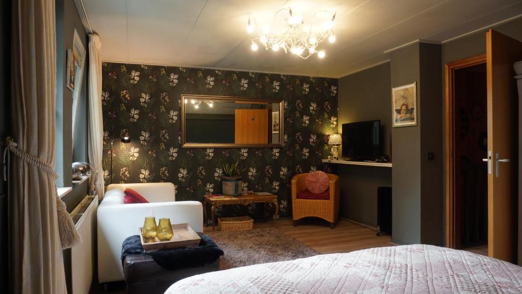 um quarto com uma cama, um sofá e uma televisão em B&B aan het bos em Ter Apel