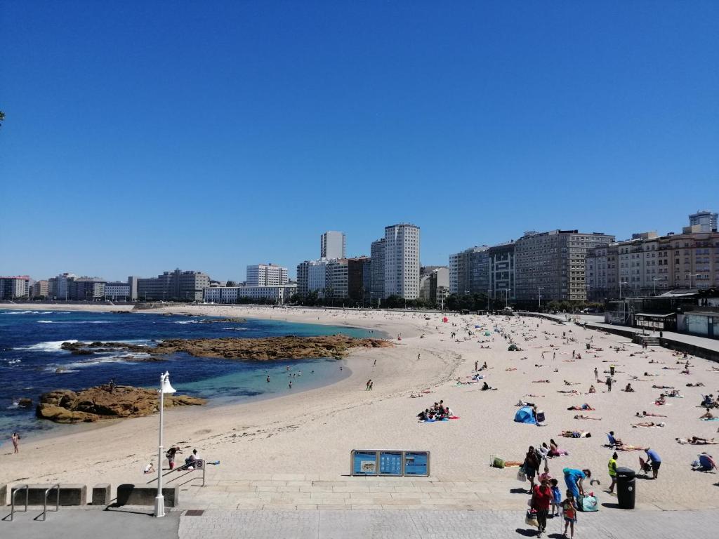 Apartamento Costa Riazor Coruña في لا كورونيا: مجموعة من الناس على شاطئ قريب من الماء