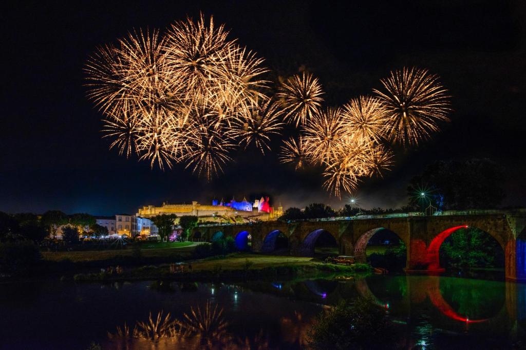 un feu d'artifice au-dessus d'une rivière avec un pont dans l'établissement SOWELL HOTELS Les Chevaliers, à Carcassonne