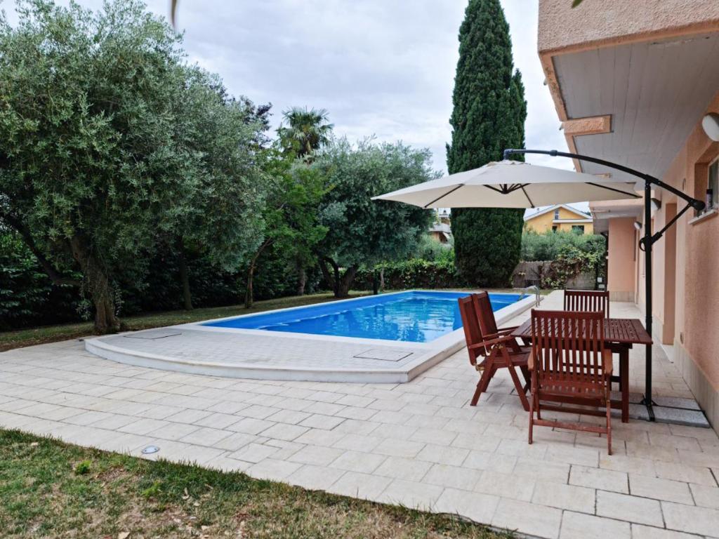 una piscina con sombrilla, mesa y sillas en Relais tra gli Ulivi, en Ortona
