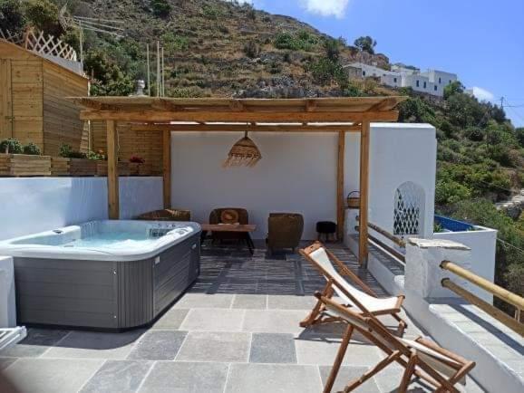 un patio con vasca idromassaggio, tavolo e sedie. di Idothea guest house ad Amorgo