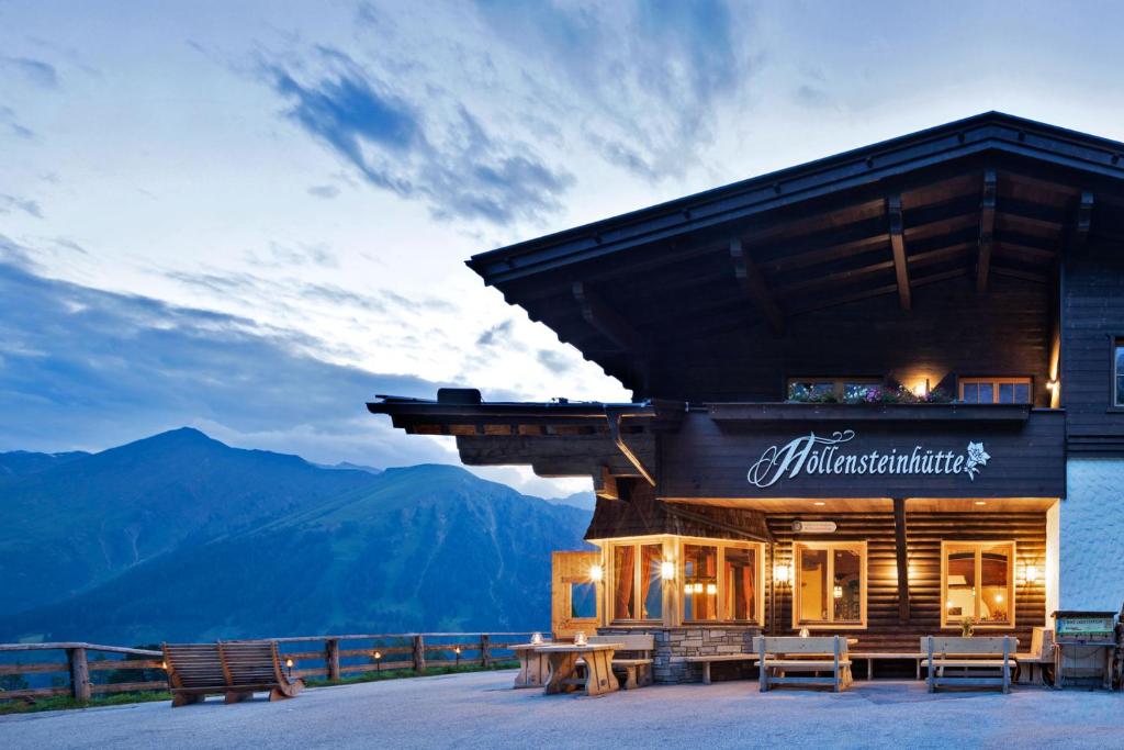 ein Gebäude mit einem Schild darauf mit Bergen im Hintergrund in der Unterkunft Berggasthaus Höllensteinhütte in Tux
