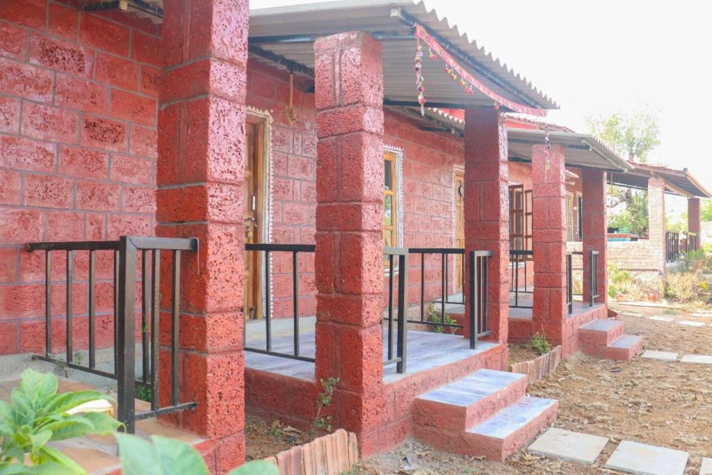 un edificio de ladrillo rojo con una puerta. en SiddhaDham - Farm Stay Cottage 1 en Nashik