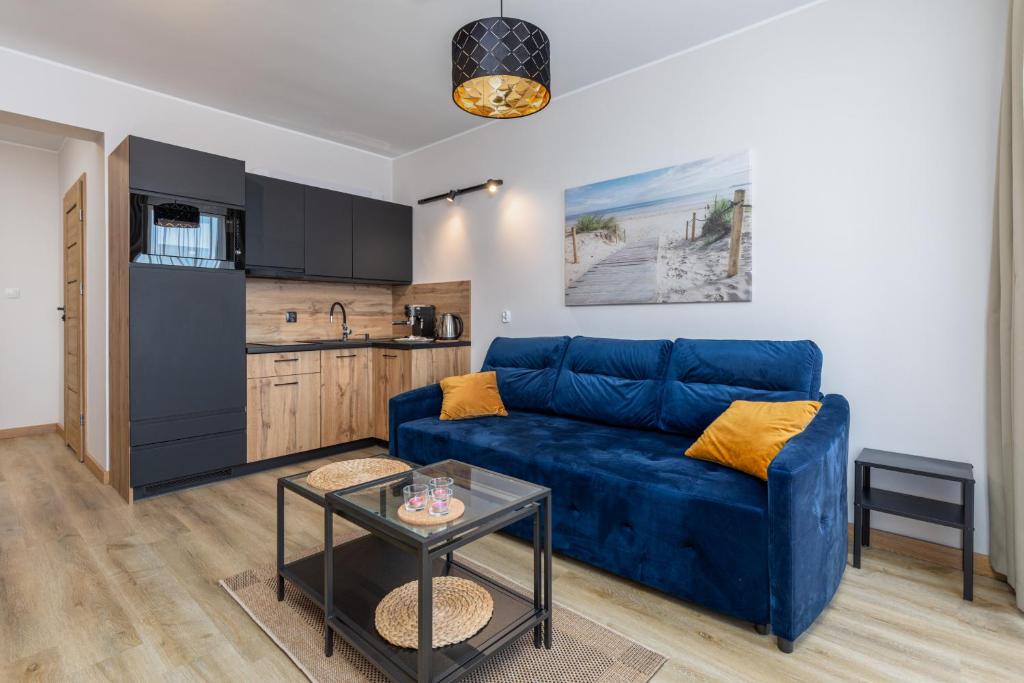 ミエルノにあるApartament 300 Planeta Mielno z garażemの青いソファとキッチンのあるリビングルーム
