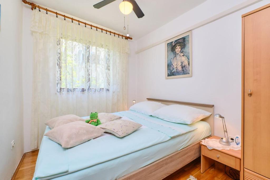 a bedroom with a blue bed with a window at Apartman Ana in Mali Lošinj