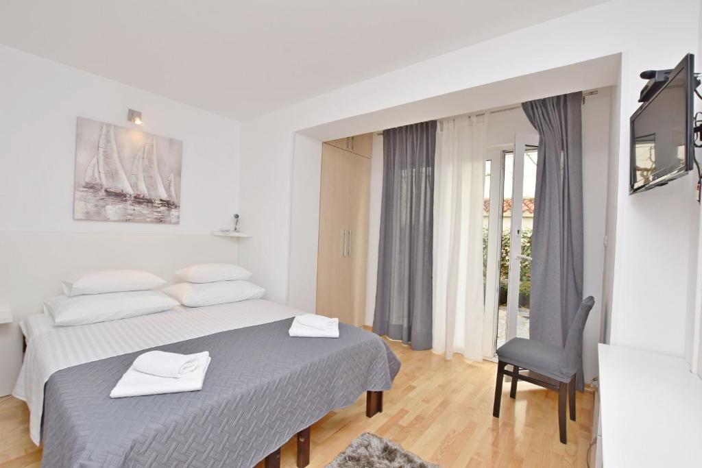een witte slaapkamer met een bed en een stoel bij Apartment Mate in Omiš