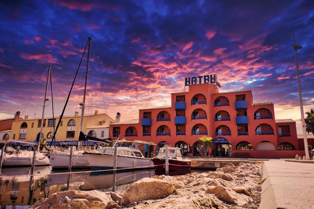 a hotel with boats docked in front of a marina at Cit'Hotel des 2 Golfs in Port Leucate