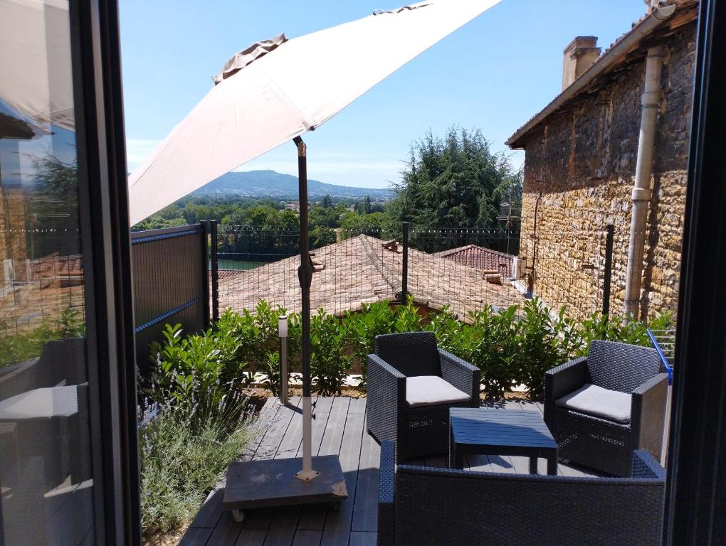 a patio with two chairs and an umbrella at Trévoux: loft ravissant avec terrasse in Trévoux