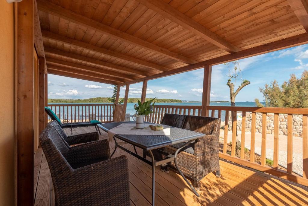 a patio with a table and chairs on a deck at Mobile home Sea Shell in Pašman