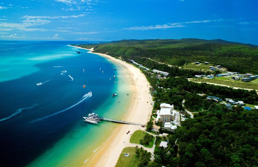 eine Luftansicht auf einen Strand mit einem Boot im Wasser in der Unterkunft Tangalooma Island Resort in Tangalooma