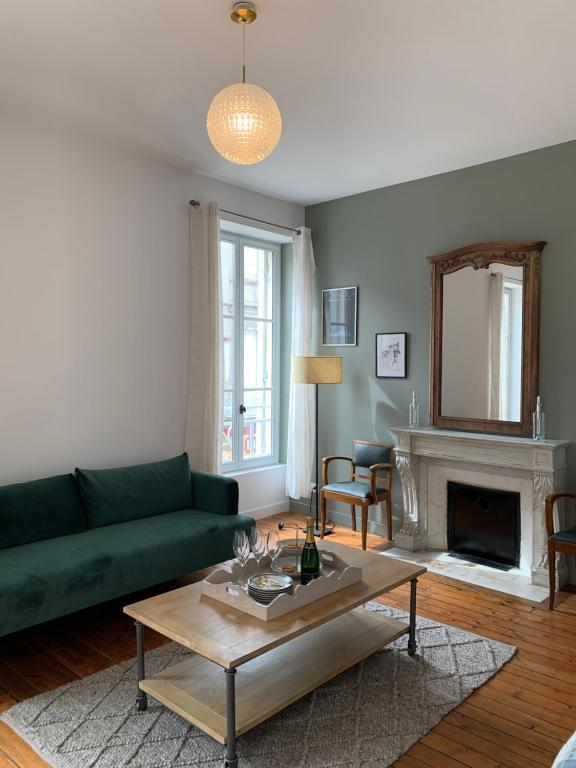 een woonkamer met een groene bank en een open haard bij Grand appartement de Standing #Hypercentre in Cognac