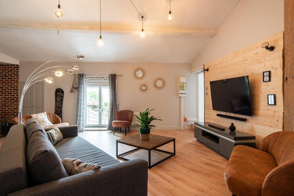 a living room with a couch and a tv at Les Nuits Lupéennes in Lupé