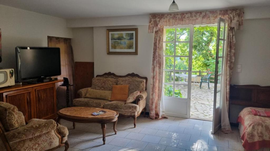 uma sala de estar com uma televisão, um sofá e uma mesa em Chambre Romantique em Domme