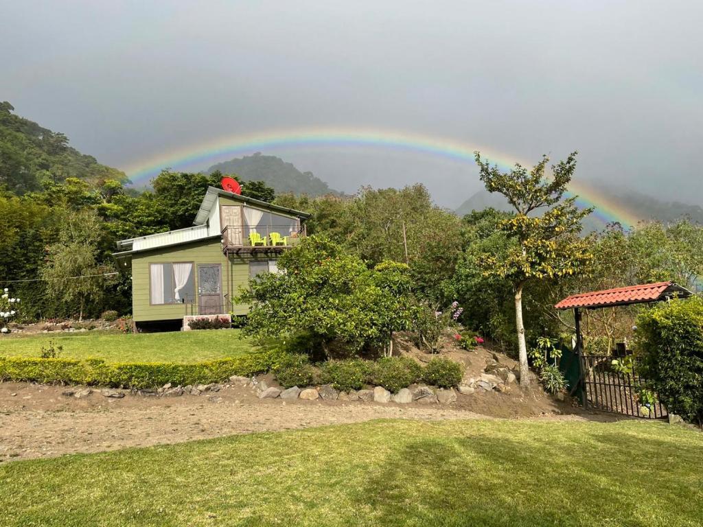 un arco iris sobre una casa con en Villa Golondrina Cabaña rodeada de Naturaleza, en Monteverde