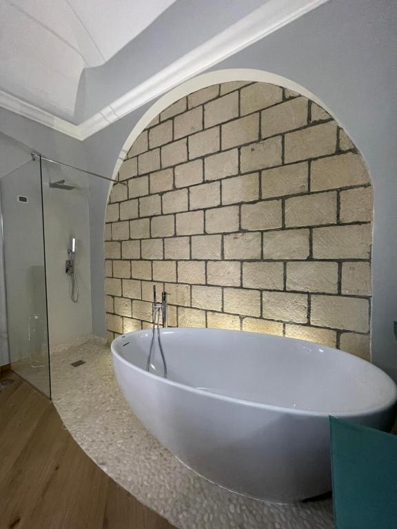 La salle de bains est pourvue d'une baignoire blanche et d'un mur en briques. dans l'établissement M&M Guest House, à Ercolano