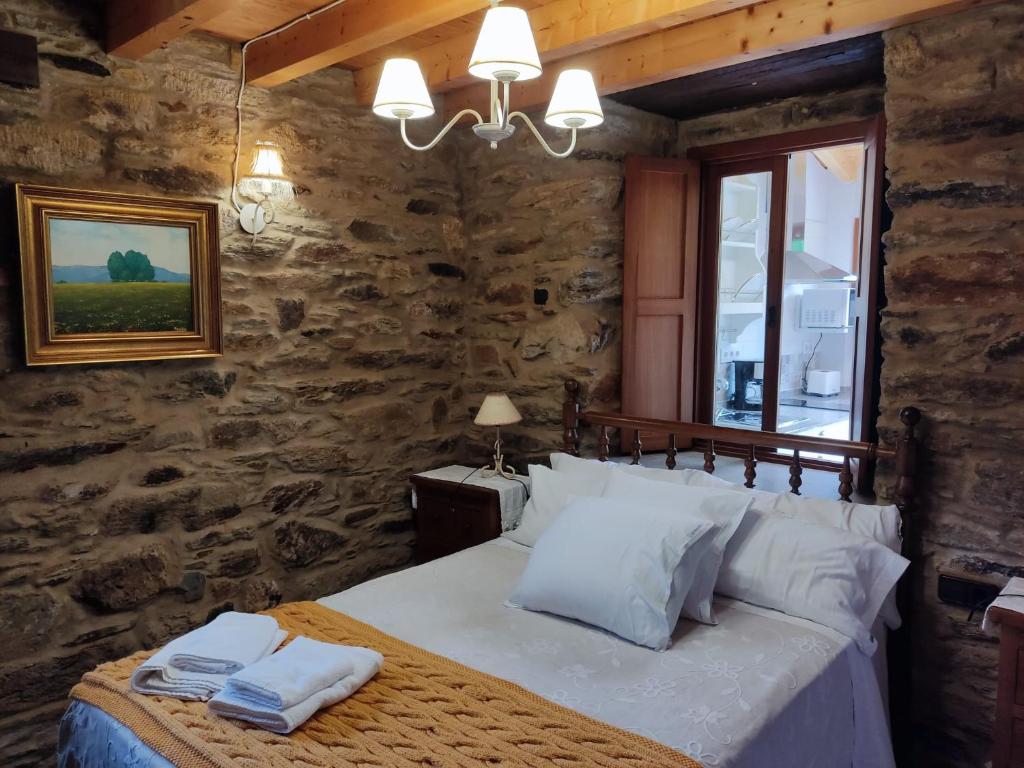 sypialnia z łóżkiem w kamiennej ścianie w obiekcie Casa Rural Penaquente w mieście Santa Marta de Ortigueira