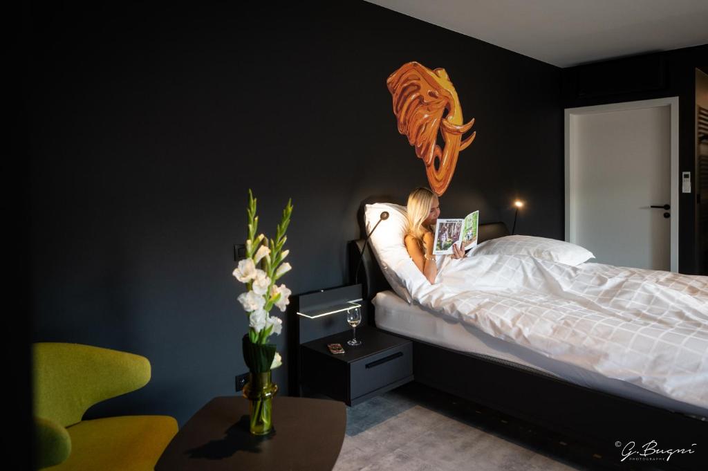 斯帕Boutique Hôtel, La Cour de la Reine, Rooftop & Bistronomique Restaurant的躺在床上读书的年轻女孩