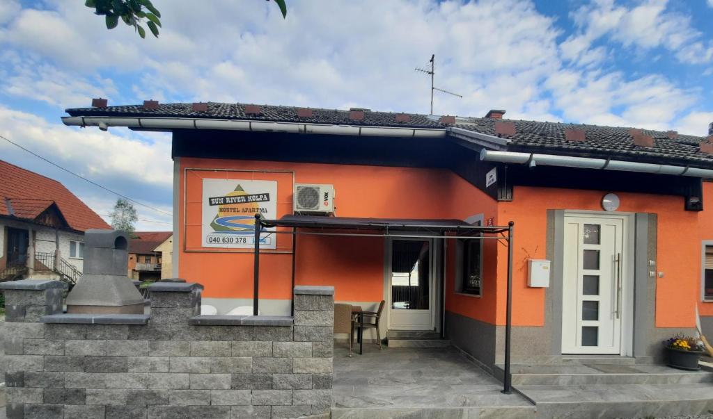 un pequeño edificio naranja con una puerta blanca en Sun river Kolpa AP1, en Vinica