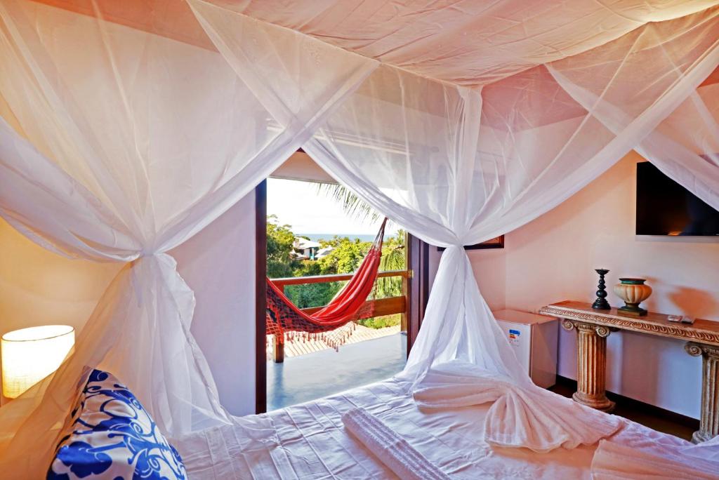 a bedroom with a canopy bed with a view of the ocean at Pousada Arraial Colonial in Arraial d'Ajuda