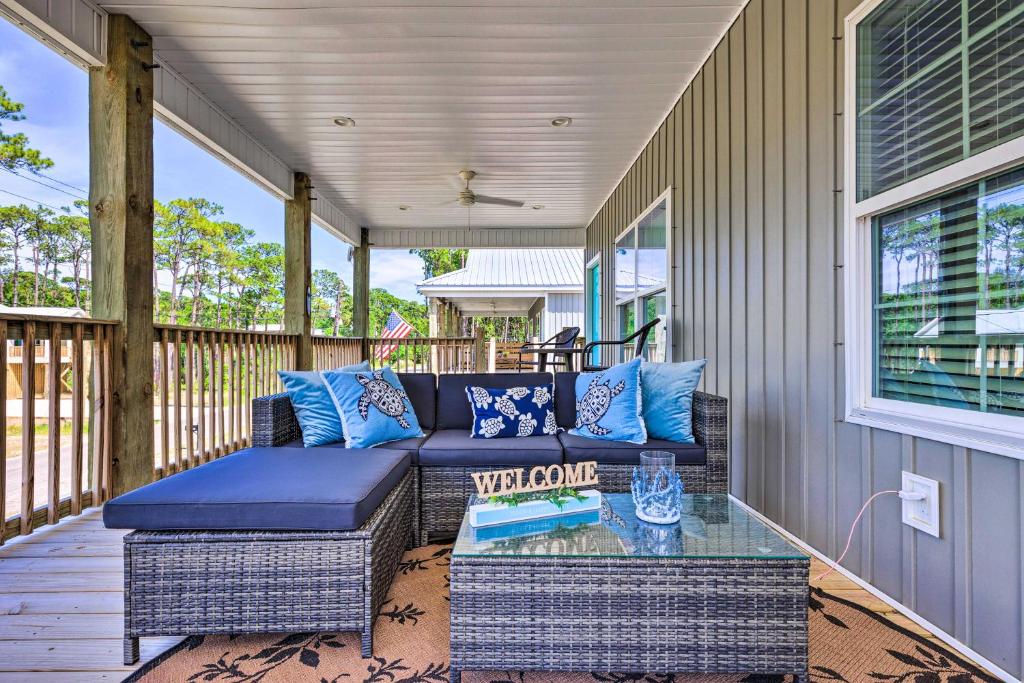 um alpendre com um sofá azul e uma mesa de vidro em Dauphin Island Retreat 2 Blocks to Beach! em Dauphin Island