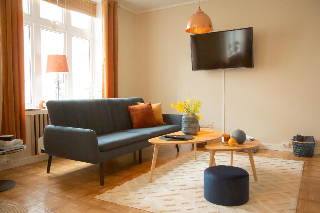a living room with a blue couch and a tv at Light Sentral Apartment Ålesund in Ålesund