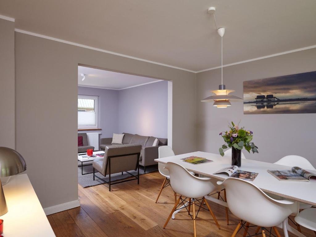 a dining room and living room with a white table and chairs at Düne 10 in Sankt Peter-Ording